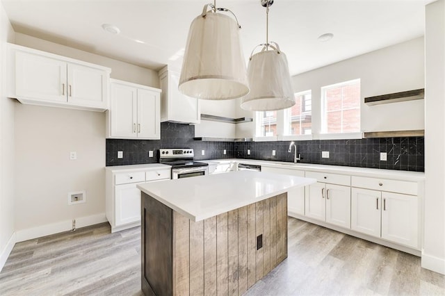 kitchen featuring a center island, stainless steel electric stove, white cabinets, decorative light fixtures, and light hardwood / wood-style floors