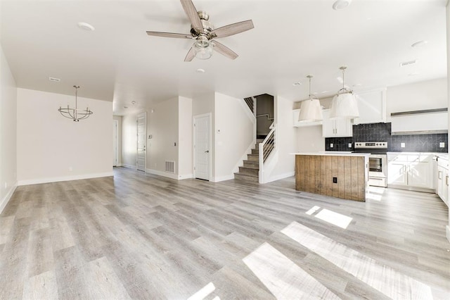 interior space featuring white cabinets, stainless steel electric range oven, hanging light fixtures, and a kitchen island