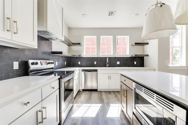 kitchen with decorative backsplash, light wood-type flooring, stainless steel appliances, sink, and white cabinets