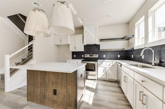 kitchen featuring white cabinetry, sink, a center island, stainless steel appliances, and light wood-type flooring