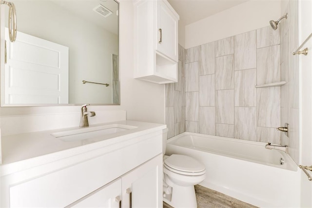 full bathroom featuring hardwood / wood-style floors, vanity, toilet, and tiled shower / bath