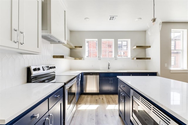 kitchen featuring stainless steel appliances, sink, blue cabinetry, decorative light fixtures, and white cabinetry