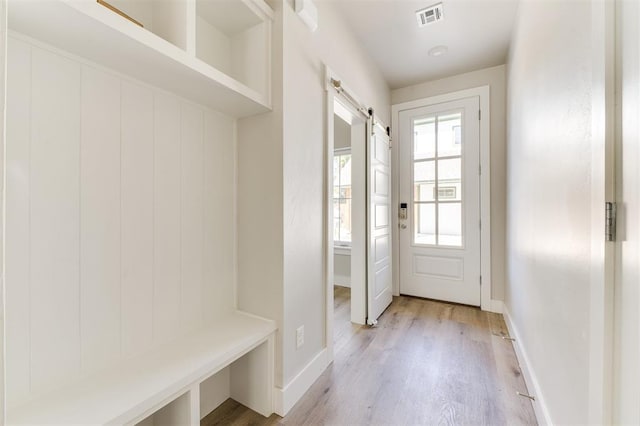 mudroom with a barn door and light wood-type flooring