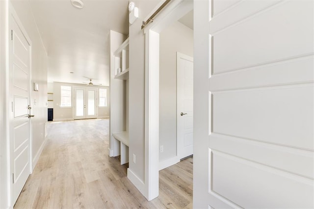 corridor with a barn door and light hardwood / wood-style floors