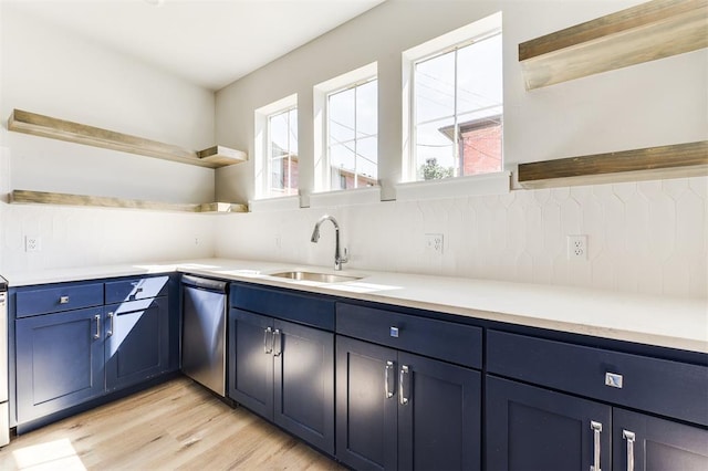 kitchen featuring decorative backsplash, light wood-type flooring, stainless steel dishwasher, sink, and blue cabinetry