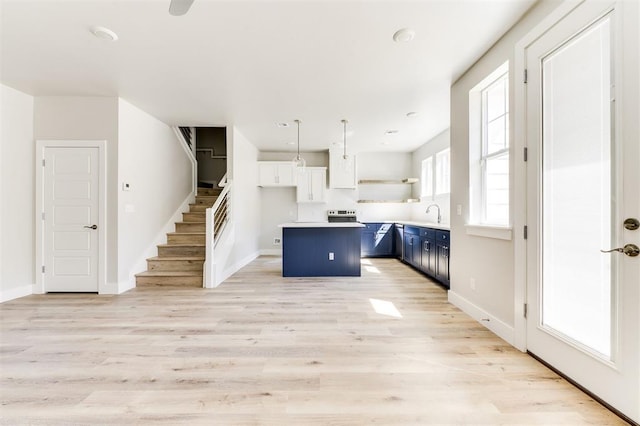 kitchen featuring blue cabinetry, a center island, light hardwood / wood-style floors, decorative light fixtures, and white cabinets