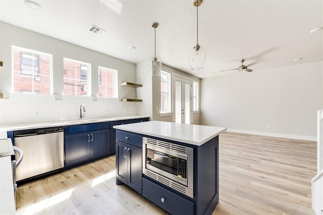 kitchen with appliances with stainless steel finishes, light wood-type flooring, blue cabinets, ceiling fan, and hanging light fixtures