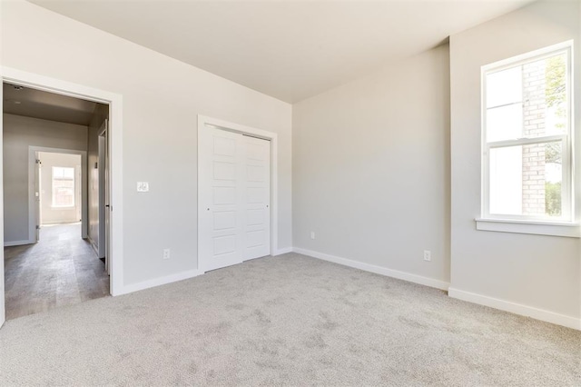 unfurnished bedroom featuring a closet, light carpet, and multiple windows