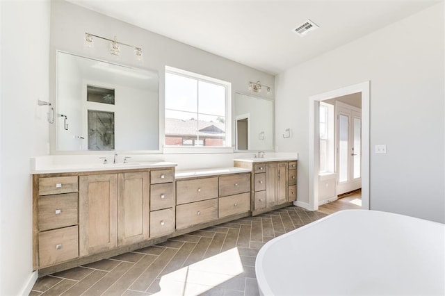 bathroom with vanity, wood-type flooring, and tiled tub