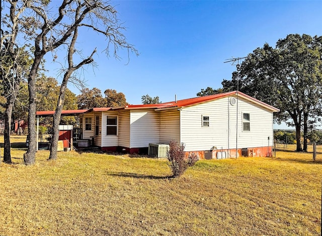 back of property with a lawn and central AC