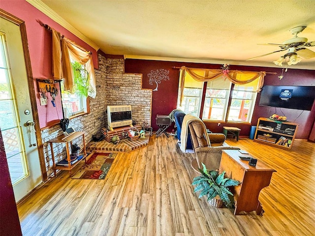 living room featuring a brick fireplace, a textured ceiling, heating unit, ceiling fan, and hardwood / wood-style flooring