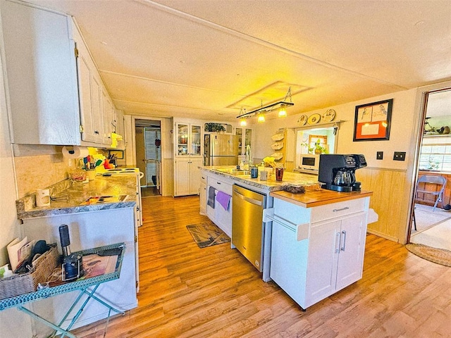 kitchen featuring light wood-type flooring, stainless steel appliances, wooden walls, white cabinetry, and butcher block counters