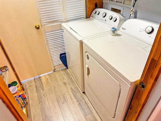 clothes washing area with washing machine and dryer and light hardwood / wood-style floors