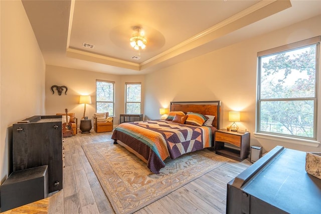 bedroom with ceiling fan, light hardwood / wood-style floors, and a raised ceiling