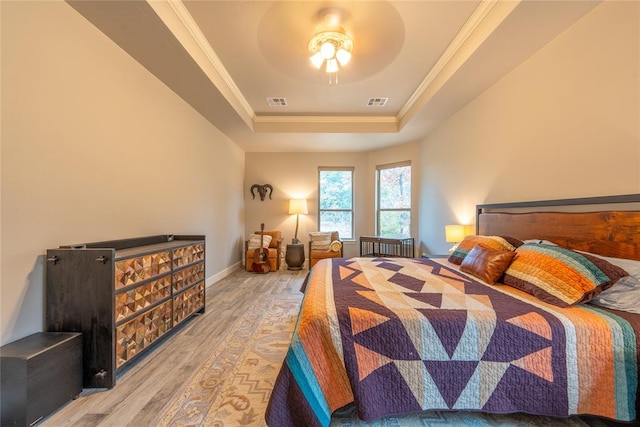 bedroom featuring a raised ceiling, ceiling fan, light hardwood / wood-style flooring, and crown molding