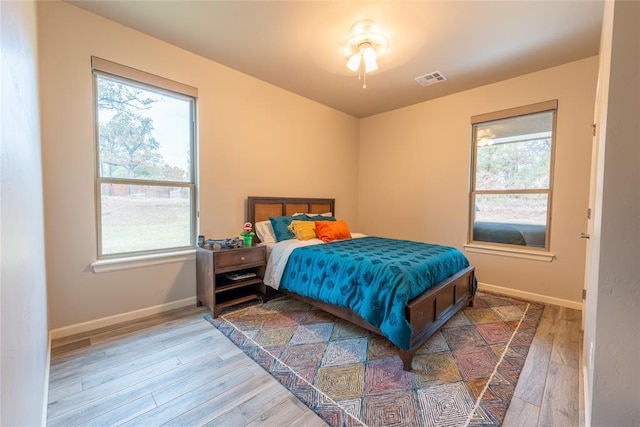 bedroom featuring hardwood / wood-style floors, ceiling fan, and multiple windows