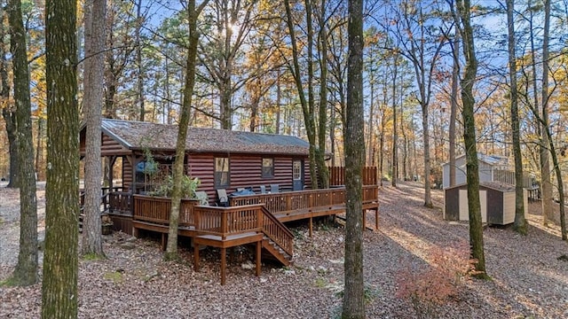 rear view of property with a storage unit and a deck