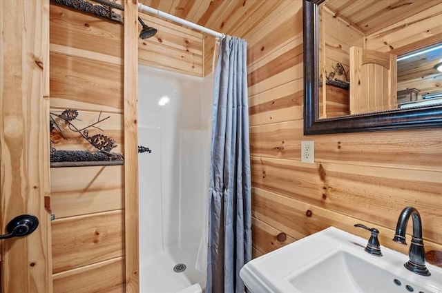 bathroom with wood walls, curtained shower, wooden ceiling, and sink