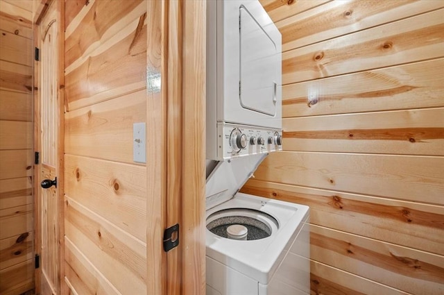 laundry area featuring stacked washer / dryer and wooden walls