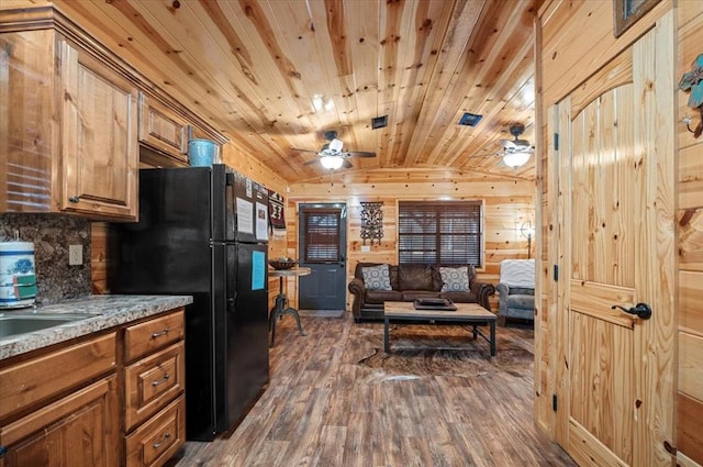 kitchen with wooden ceiling, black refrigerator, wooden walls, vaulted ceiling, and dark hardwood / wood-style flooring