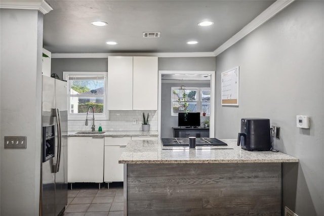 kitchen with stainless steel fridge with ice dispenser, sink, white cabinets, and light stone counters