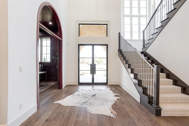 entryway with a towering ceiling and dark wood-type flooring