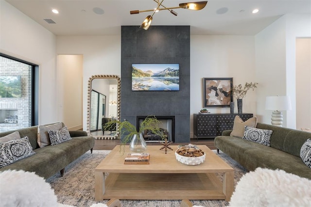 living room with a tile fireplace, hardwood / wood-style floors, and a notable chandelier