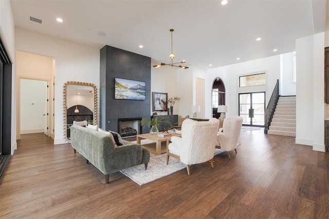 living room featuring a large fireplace, hardwood / wood-style floors, and a notable chandelier