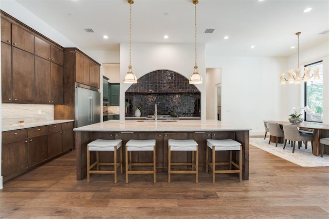 kitchen featuring a large island with sink, hanging light fixtures, and wood-type flooring