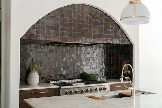 interior space with decorative backsplash, range, and sink