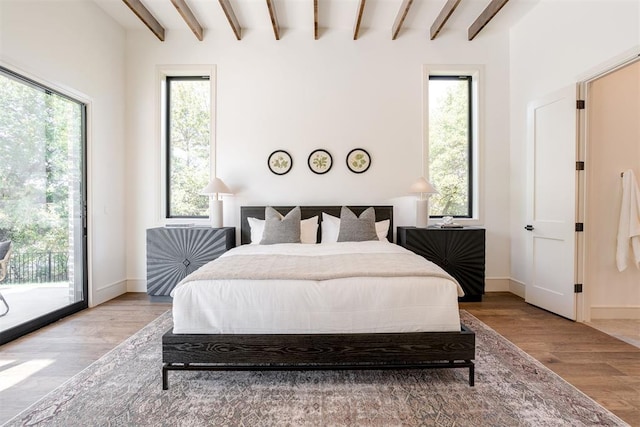 bedroom with access to outside, light hardwood / wood-style floors, and beam ceiling