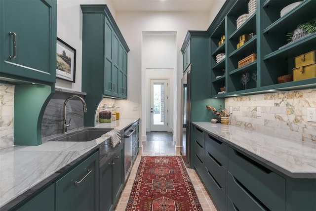 kitchen with backsplash, light stone counters, stainless steel appliances, sink, and green cabinetry