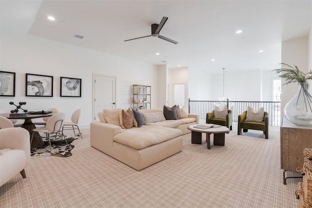 living room featuring ceiling fan with notable chandelier and light colored carpet