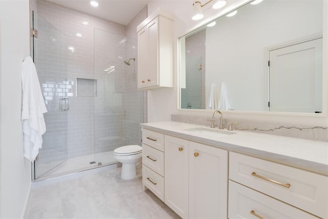 bathroom featuring vanity, a shower with shower door, and toilet