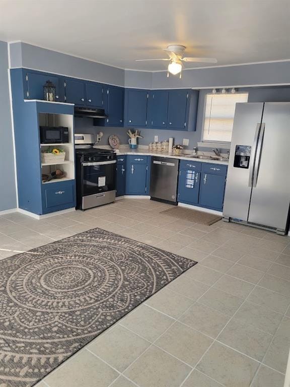 1201 California Ave, Chickasha, OK 73018 - kitchen with stainless steel appliances, blue cabinets, light countertops, light tile patterned floors, and ceiling fan