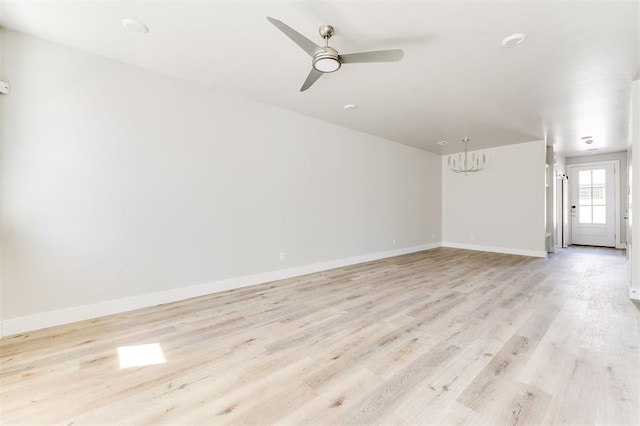 spare room with light hardwood / wood-style floors and ceiling fan with notable chandelier