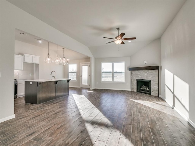 living room with sink, ceiling fan with notable chandelier, dark wood-type flooring, and lofted ceiling