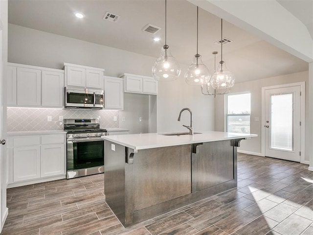 kitchen with decorative light fixtures, sink, an island with sink, and appliances with stainless steel finishes