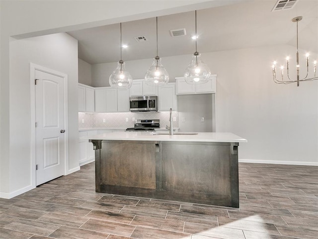 kitchen with hanging light fixtures, sink, an island with sink, and stainless steel appliances