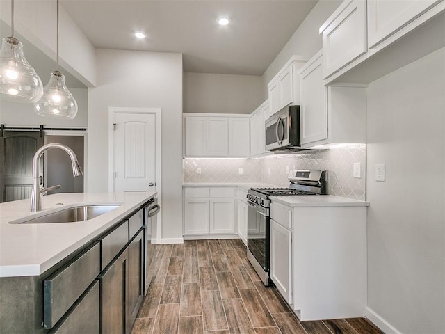 kitchen with appliances with stainless steel finishes, dark wood-type flooring, sink, decorative light fixtures, and white cabinetry