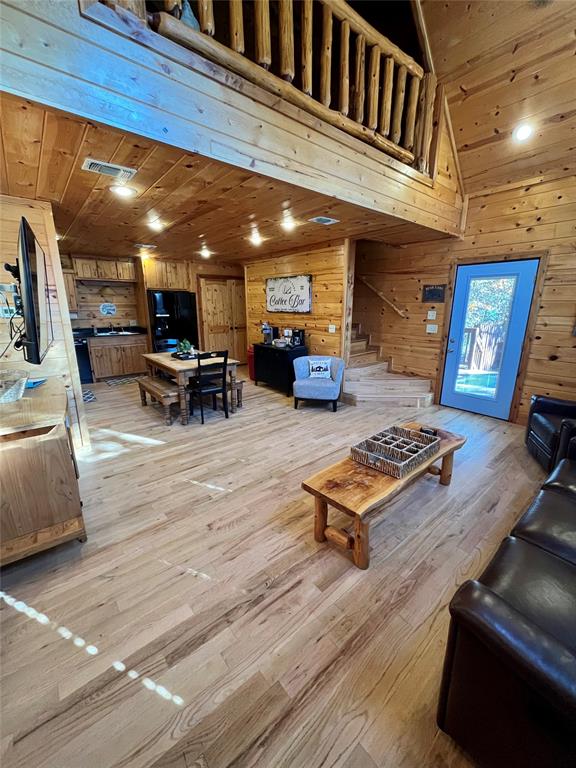 living room featuring light wood-type flooring, wooden walls, and wood ceiling