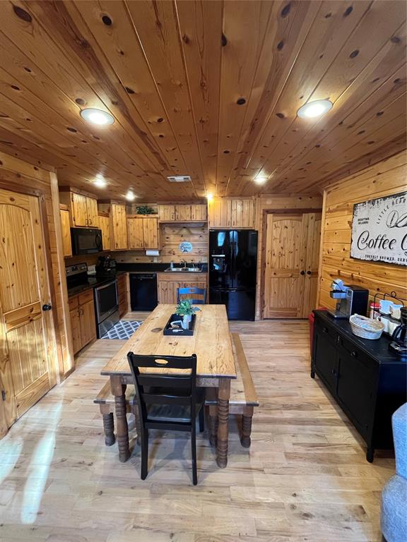 dining room with wooden walls and light hardwood / wood-style flooring