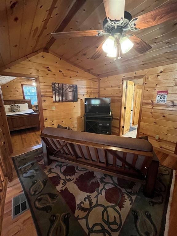 living room featuring ceiling fan, wooden walls, hardwood / wood-style flooring, wooden ceiling, and vaulted ceiling with beams