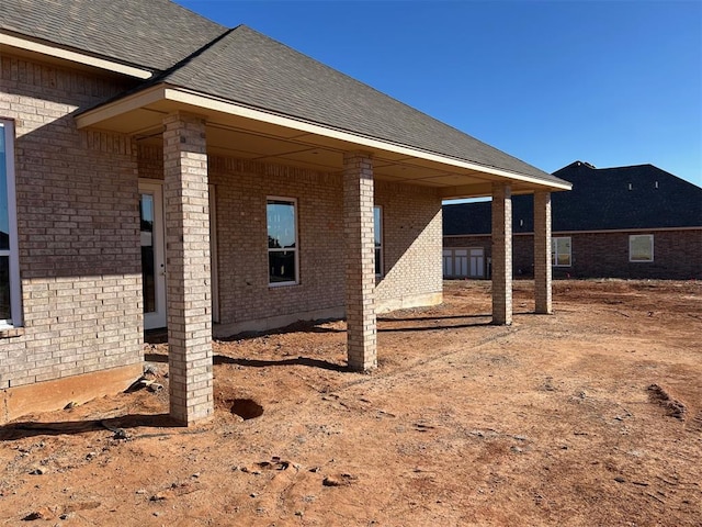 view of home's exterior featuring brick siding and roof with shingles