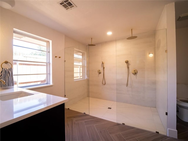 bathroom with vanity, toilet, and tiled shower