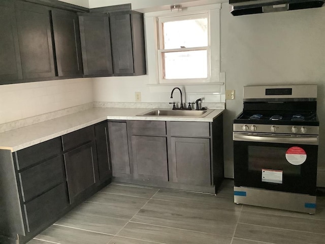 kitchen featuring extractor fan, light tile patterned floors, stainless steel range with gas cooktop, and sink