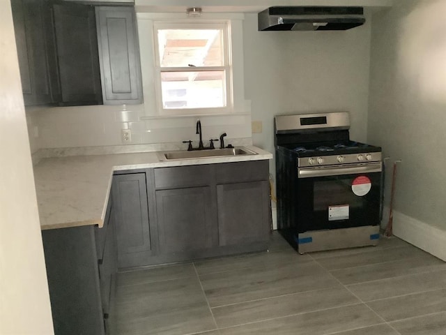 kitchen with sink, gray cabinets, light tile patterned floors, gas stove, and extractor fan