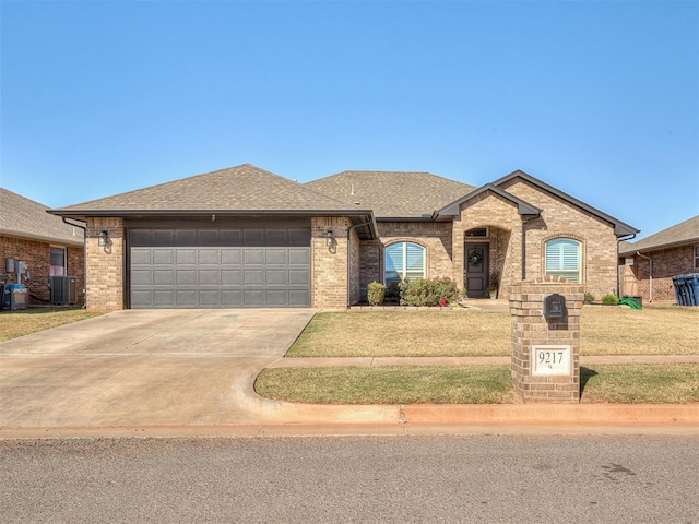 view of front of house featuring a garage, central air condition unit, and a front lawn