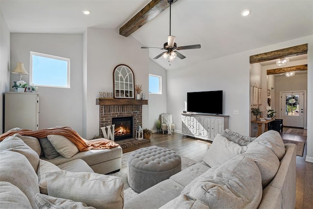 living room featuring beam ceiling, a fireplace, dark hardwood / wood-style flooring, and a healthy amount of sunlight