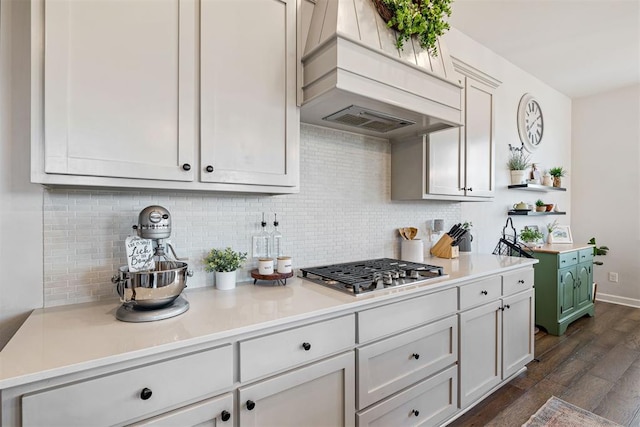 kitchen with tasteful backsplash, premium range hood, stainless steel gas cooktop, white cabinets, and dark hardwood / wood-style floors